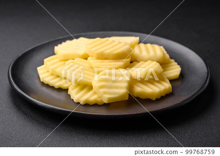 Raw fresh potatoes cut into slices on a black ceramic plate 99768759