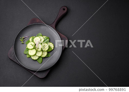Delicious healthy raw cucumber sliced on a black ceramic plate 99768891