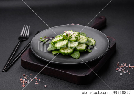 Delicious healthy raw cucumber sliced on a black ceramic plate 99768892