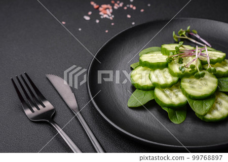 Delicious healthy raw cucumber sliced on a black ceramic plate 99768897