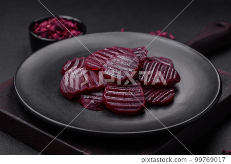 Delicious healthy boiled ruby-colored beets sliced on a black plate 99769017