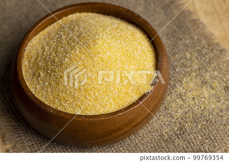 Round wooden bowl with dry corn flour 99769354