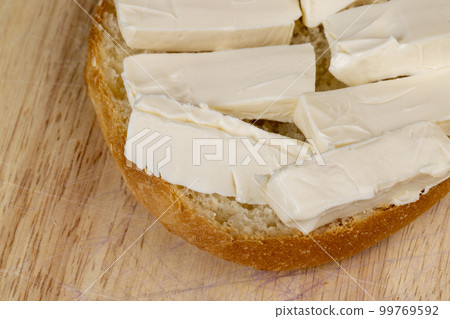 Wheat bun with large pieces of processed cheese inside 99769592