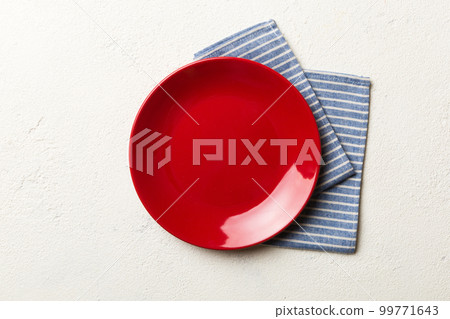Top view on colored background empty round red plate on tablecloth for food. Empty dish on napkin with space for your design Top view on colored background empty round red plate on tablecloth for food. Empty dish on napkin with space for your design 99771643