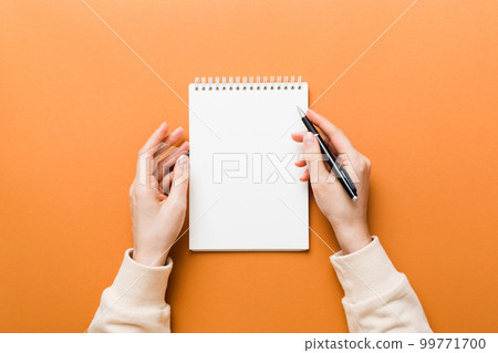 Woman hand with pencil writing on notebook. Woman working on office table. Female hand holding pencil and sketchbook. Mock-up Concept 99771700