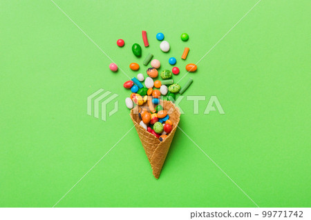 waffle cone full of assorted traditional candies falling out on colored background with copy space. Happy Holidays sale concept 99771742