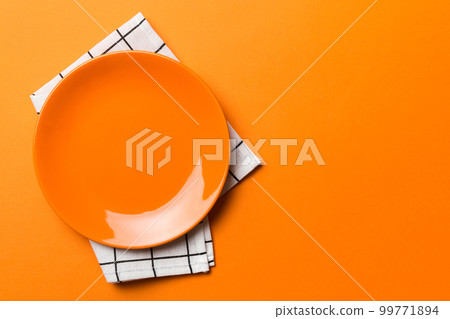 Top view on colored background empty round red plate on tablecloth for food. Empty dish on napkin with space for your design Top view on colored background empty round red plate on tablecloth for food. Empty dish on napkin with space for your design 99771894