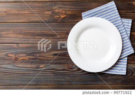 Top view on colored background empty round white plate on tablecloth for food. Empty dish on napkin with space for your design Top view on colored background empty round white plate on tablecloth for food. Empty dish on napkin with space for your design 99771922
