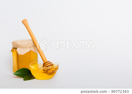 Honey in jar with leaves and honey dipper on colored background top view with copy text 99772163