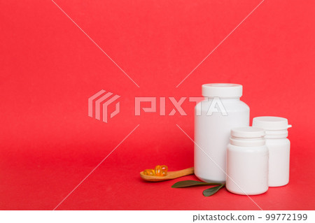 Omega-3 capsules lie in white bottle on a table with green leaves background. Fish oil tablets. Biologically active additives. omega 6, omega 9, vitamin A, E, D, vitamin D3 top view with copy space 99772199