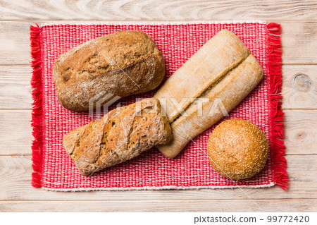 Assortment of freshly baked bread with napkin on rustic table top view. Healthy unleavened bread. French bread Assortment of freshly baked bread with napkin on rustic table top view. Healthy unleavened bread. French bread 99772420
