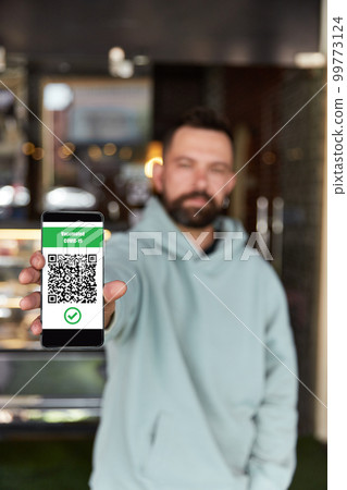 Man showing Qr Code on entrance to the restaurant. Digital vaccination certificate on smartphone. New normal 99773124