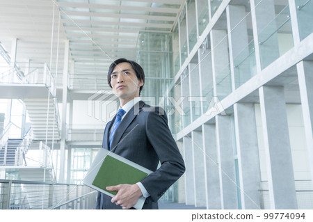 Portrait of businessman standing in office building 99774094