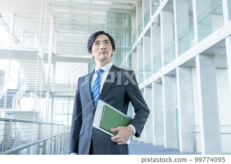 Portrait of businessman standing in office building 99774095