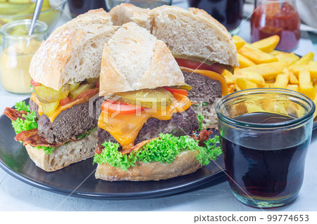 Pieces of huge giant homemade cheeseburger for burger party on plate, horizontal 99774653