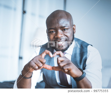 Romantic Office Manager Makes Heart of his Fingers and his eyes are Full of Love. Charming Guy Shows Heart-hand Symbol Close-up Portrait. Blurred Background. High quality photo Romantic Office Manager Makes Heart of his Fingers and his eyes are Full of Love. Charming Guy Shows Heart-hand Symbol Close-up Portrait. Blurred Background. High quality photo 99775355