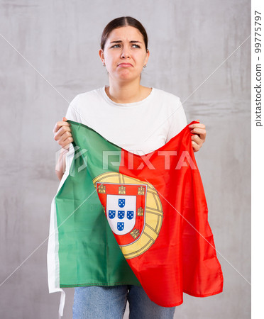 Sad young woman holding Portugal flag against unicoloured background 99775797
