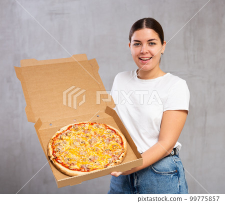 Photo of pizza held by smiling young woman against gray background 99775857