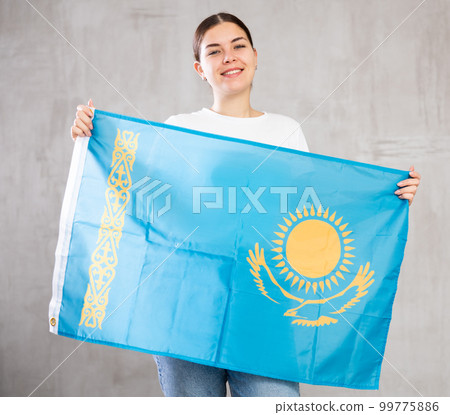 Cheerful young woman holding flag of Kazakhstan against gray background indoors 99775886