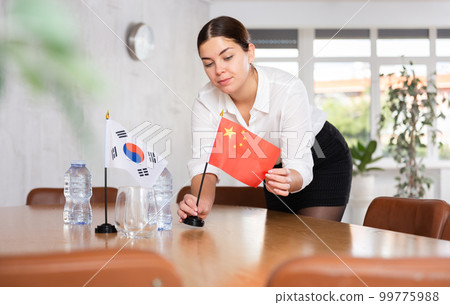 Preparing for business negotiations - woman sets small flags of countries of China and South Korea on table Preparing for business negotiations - woman sets small flags of countries of China and South Korea on table 99775988