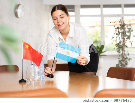 Young female attendant putting up flags for international negotiations between china and argentina Young female attendant putting up flags for international negotiations between china and argentina 99776483