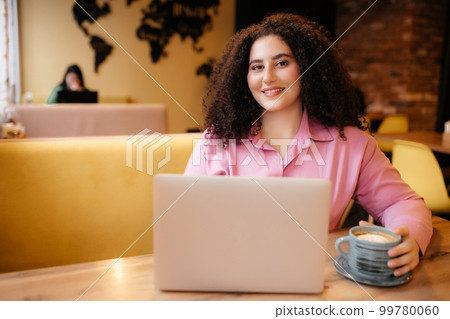 Portrait of a beautiful plump woman drinking a cup of coffee in a cafe. 99780060