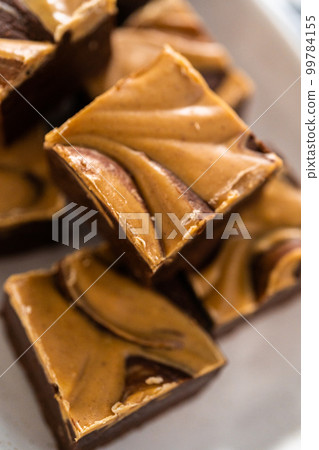 Homemade chocolate fudge with peanut butter swirl pieces on a white serving plate. Homemade chocolate fudge with peanut butter swirl pieces on a white serving plate. 99784155