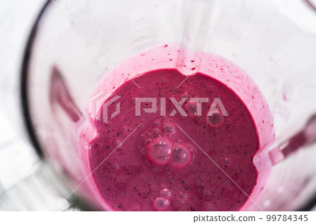 Mixing ingredients in kitchen blender to prepare mixed berry boba smoothie. 99784345