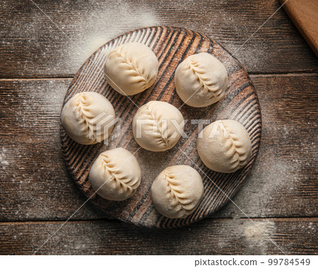 Semi finished manti dumplings on board with flour 99784549