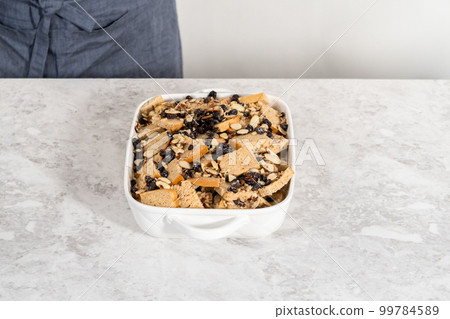 Baking bread pudding with raising and almond slivers in a white casserole dish. 99784589