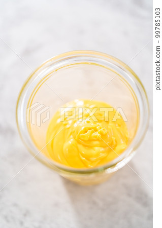 Melted yellow chocolate chips in a glass jar on the kitchen counter. Melted yellow chocolate chips in a glass jar on the kitchen counter. 99785103