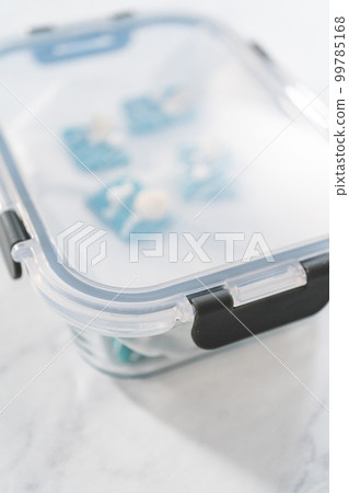 Packaging mini mermaid chocolate bars into a food glass container for storage. 99785168