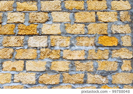 Stone bricks from limestone laid, cement, yellow brown background texture. Natural rough stone wall texture, front view, full frame, close-up 99788048