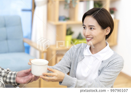 Caregiver giving tea 99790107