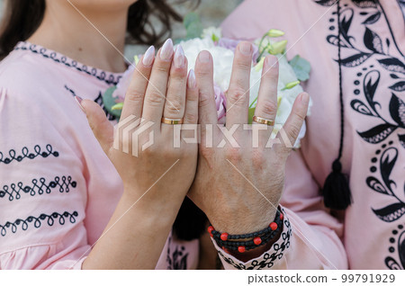 Wedding rings on the hands of the newlyweds. Golden rings on the hands of a guy and a girl Wedding rings on the hands of the newlyweds. Golden rings on the hands of a guy and a girl 99791929