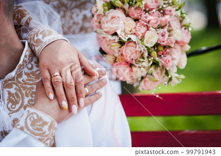 Wedding rings on the hands of the newlyweds. Golden rings on the hands of a guy and a girl 99791943