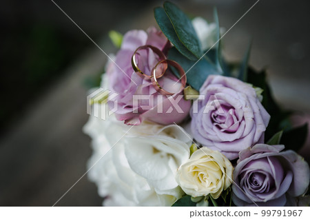 A pair of gold wedding rings on a bride's bouquet with colorful flowers A pair of gold wedding rings on a bride's bouquet with colorful flowers 99791967