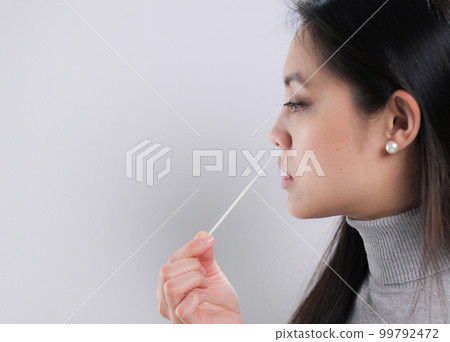 Young woman takes a sample from her nose for a corona test 99792472
