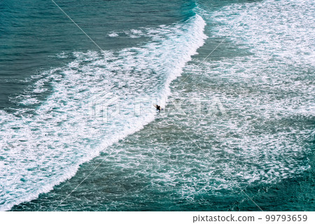 Aerial view of surfers surfing waves in Beach of Antuerta in Ajo Aerial view of surfers surfing waves in Beach of Antuerta in Ajo 99793659