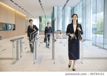 男性和女性商人通過安全門進入辦公樓 99794181