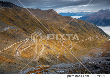 Stelvio pass, mountain road dramatic landscape at dawn above mist, Italy Stelvio pass, mountain road dramatic landscape at dawn above mist, Italy 99794910