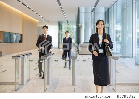 男性和女性商人通過安全門進入辦公樓 99795382