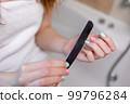 The girl makes herself a manicure sitting in the bathroom, she saws multi-colored nails with a file. High quality photo 99796284