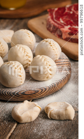 Semi finished manti dumplings on board with flour 99796618