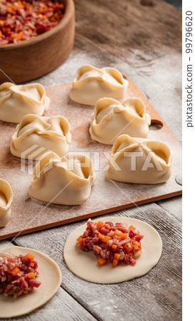 Semi finished manti dumplings on board with flour Semi finished manti dumplings on board with flour 99796620