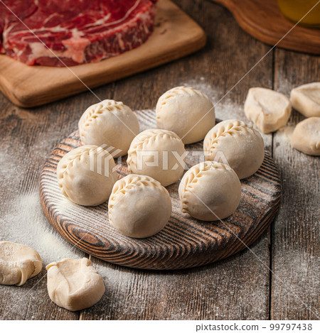 Semi finished manti dumplings on board with flour 99797438