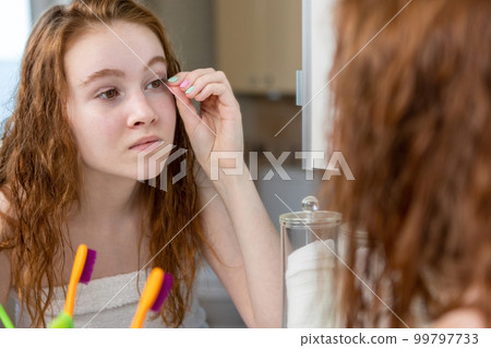 A young teenage girl washes and takes care of her face in the bathroom. High quality photo A young teenage girl washes and takes care of her face in the bathroom. High quality photo 99797733