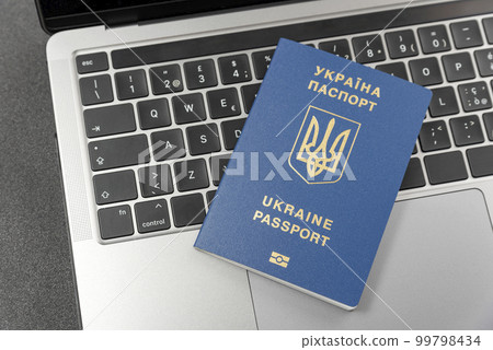 Ukrainian passport on laptop keyboard. Top view. Online registration for Ukrainians. Online visa or immigration for citizens of Ukraine 99798434
