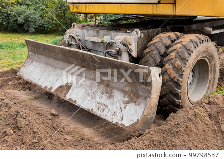 Excavator or bulldozer bucket flattens the ground or road in the industrial zone or construction site 99798537