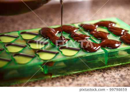 Putting chocolate in mold Putting chocolate in mold 99798659